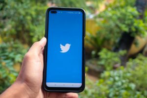 hand holding a smartphone with twitter icon on screen iphone with a social media app logo