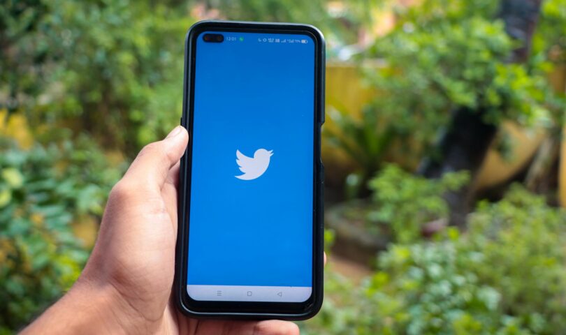 hand holding a smartphone with twitter icon on screen iphone with a social media app logo